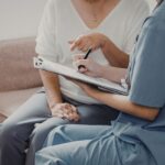 Profesional sanitaria revisando documentación con paciente sobre permiso por hospitalización de familiar